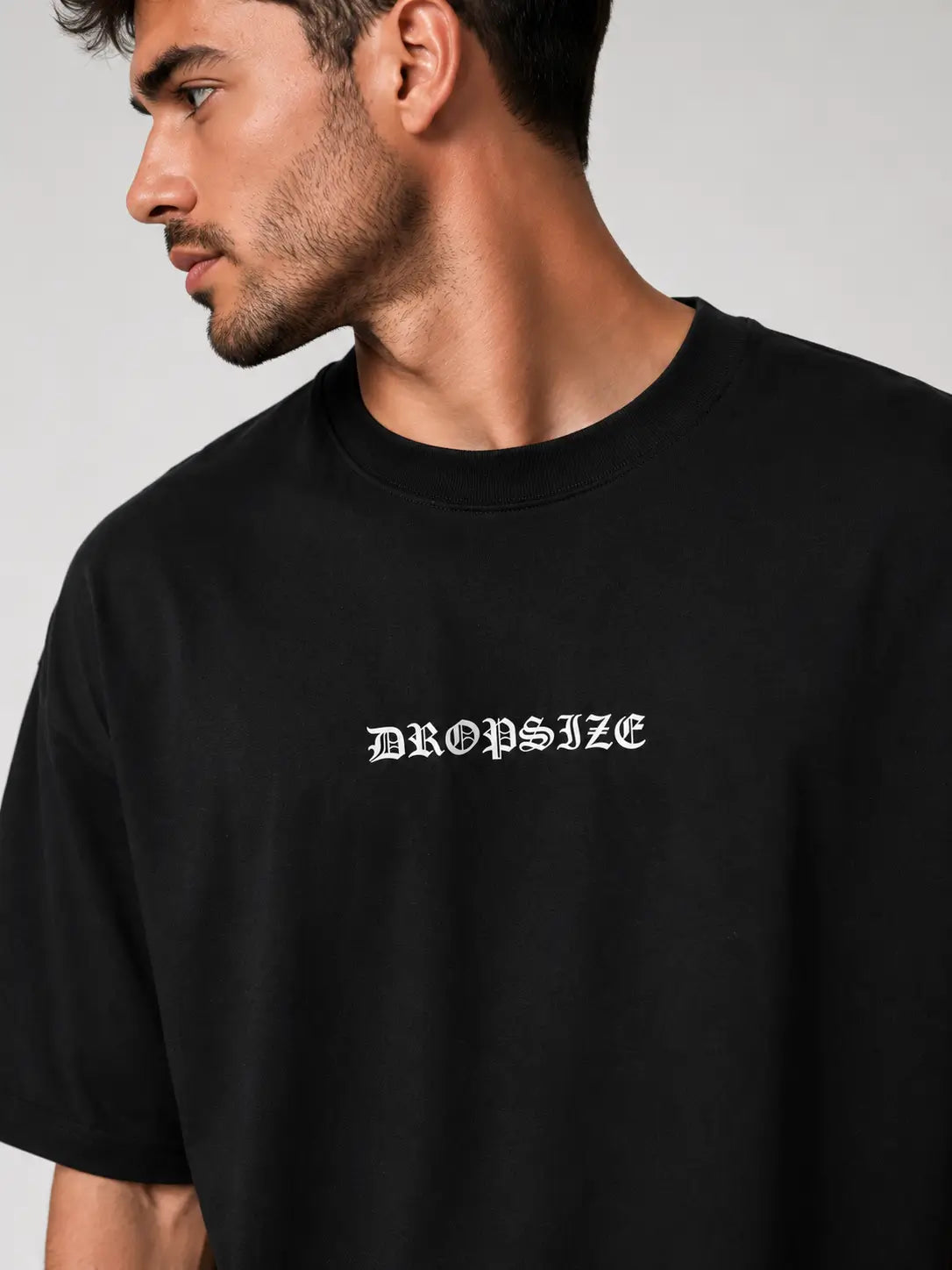 Close-up front view of a black oversized T-shirt featuring a minimal chest graphic print with a relaxed streetwear fit