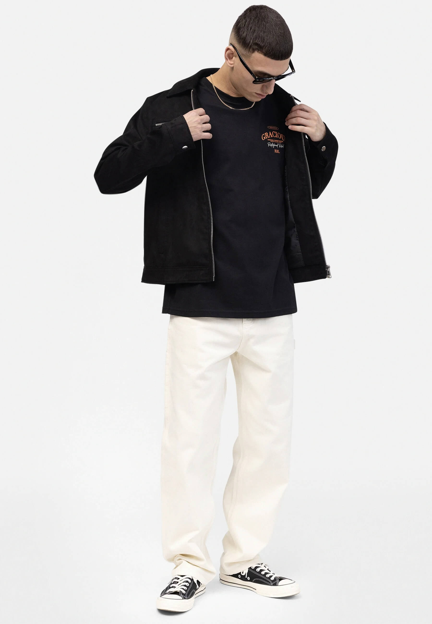 Lifestyle image of a model wearing a black oversized T-shirt with a minimal chest graphic print and relaxed streetwear fit.